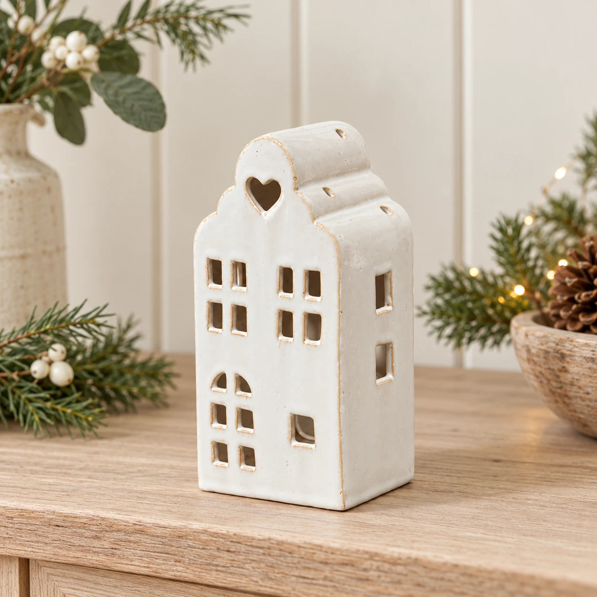 Empty unlit white ceramic townhouse tealight holder on an oak Christmas dresser