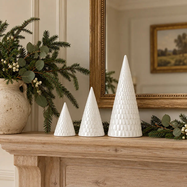 Three white ceramic tree decorations on a country home mantel