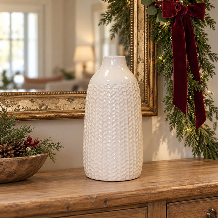 White leaf-patterned ceramic vase displayed on an oak console with Christmas greenery