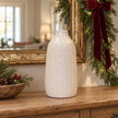 White leaf-patterned ceramic vase displayed on an oak console with Christmas greenery