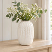 Medium warm white ceramic leaf vase, 24cm tall, styled with white flowers and eucalyptus on a pale oak console.