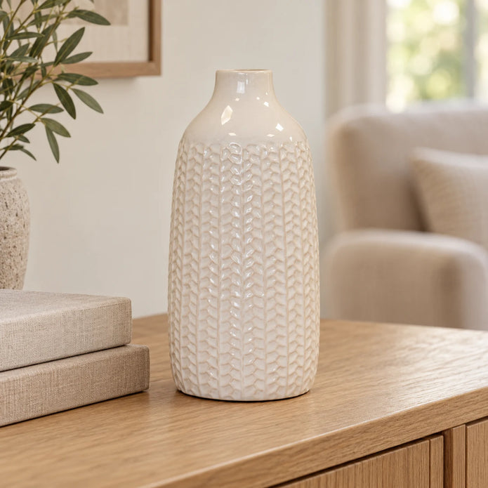White leaf-patterned vase displayed empty beside neutral books in a bright living room