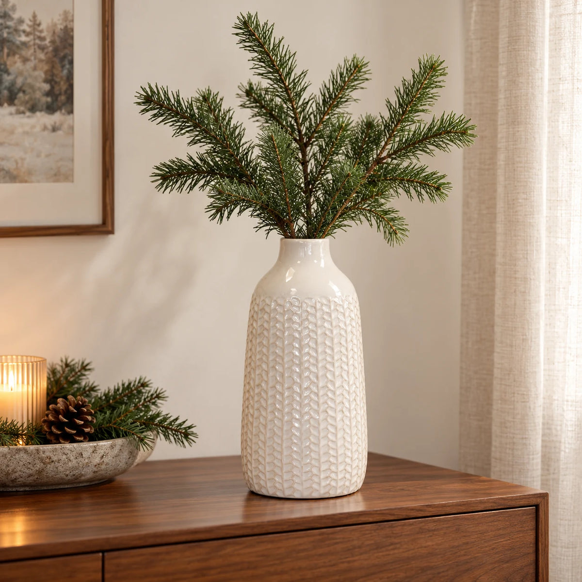 Medium white ceramic leaf vase holding faux fir stems on a walnut sideboard
