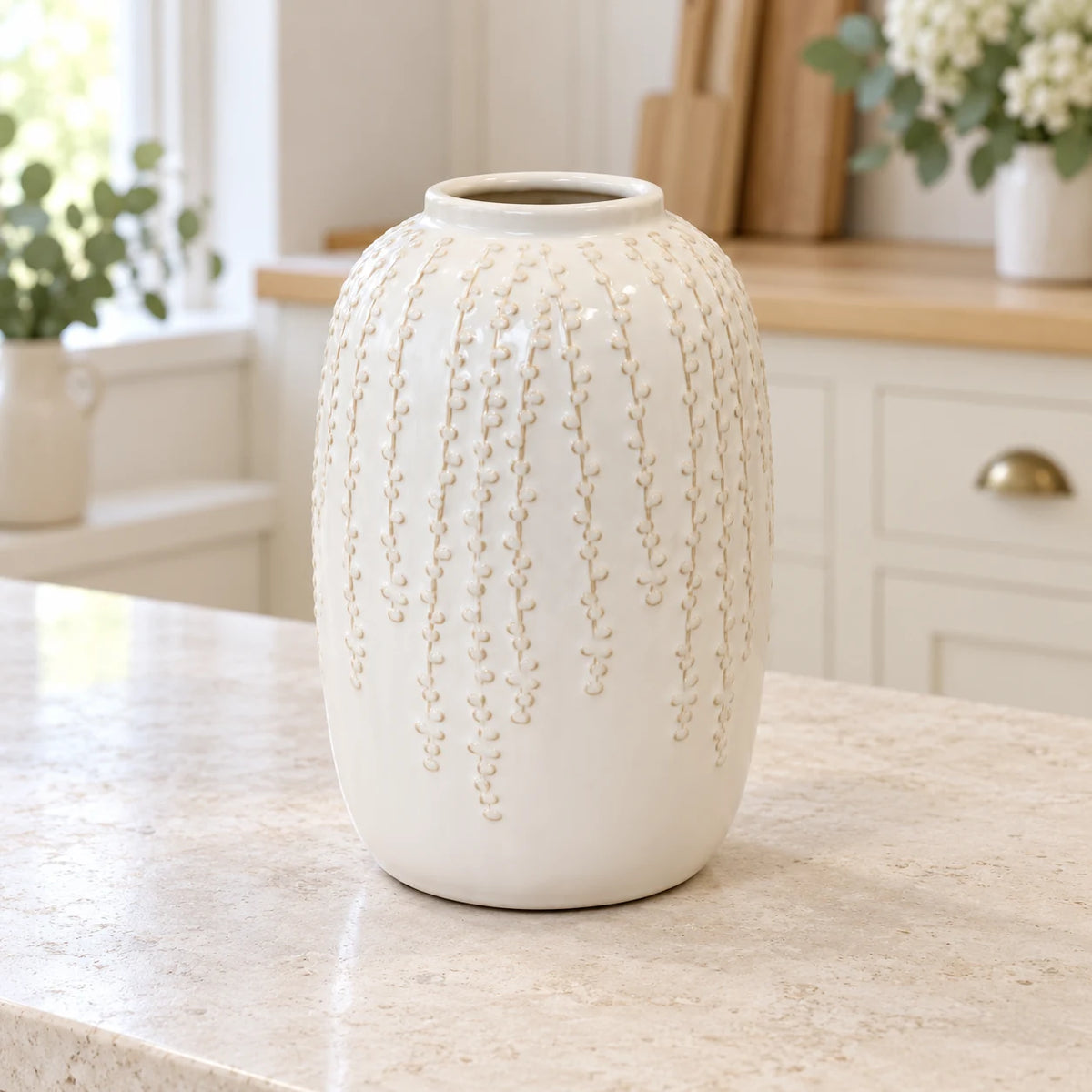 Medium warm white ceramic leaf vase, 24cm tall, styled empty in a bright neutral kitchen.