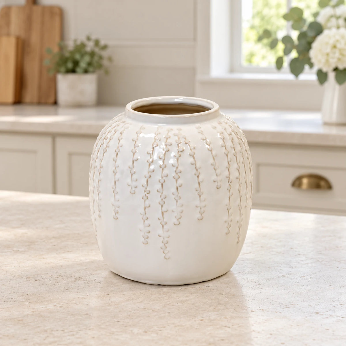 Small warm white ceramic leaf vase, 18cm tall, styled empty in a bright neutral kitchen.