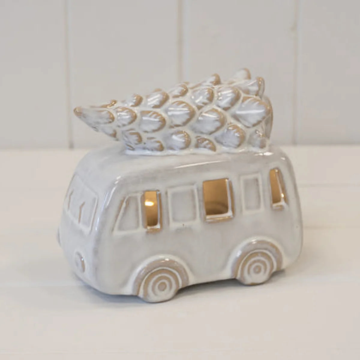 White ceramic LED camper van with Christmas tree on roof on a plain studio background, unlit