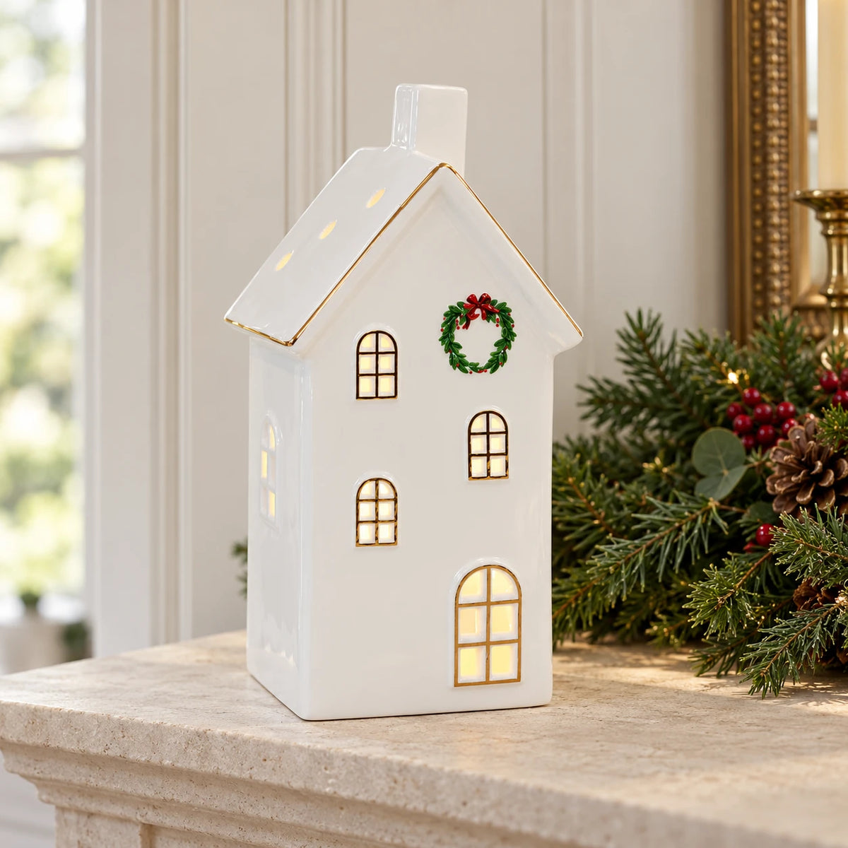Large white LED Christmas house on a limestone mantel with greenery