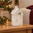 Medium white LED house on an oak side table beside a burgundy throw