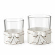 Studio close-up of distressed white metal bows and clear glass on the small and large tealight holders