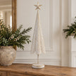 Extra large white metal Christmas tree with gold star details on an oak console.