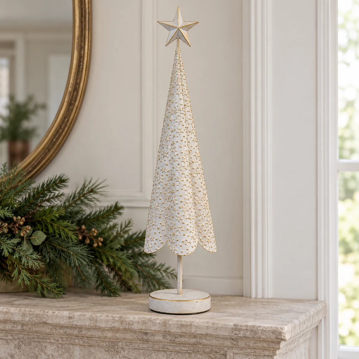 White metal Christmas tree with gold stars styled on a stone mantel.