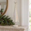 White metal Christmas tree with gold stars styled on a stone mantel.