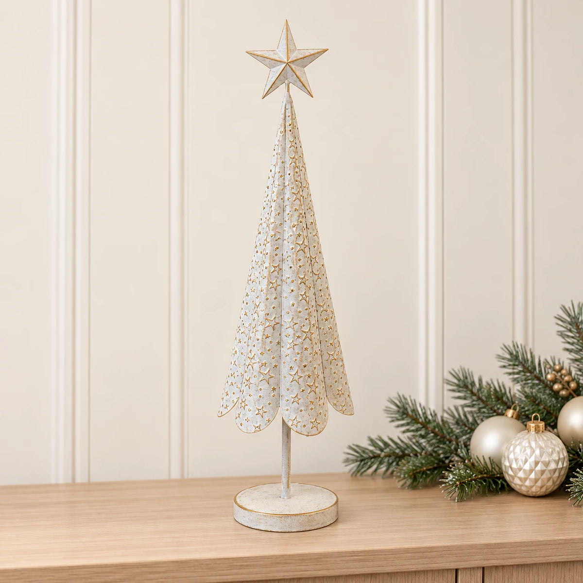 Large white metal Christmas tree with gold stars on a pale oak console with festive greenery