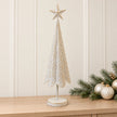 Large white metal Christmas tree with gold stars on a pale oak console with festive greenery