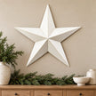 Extra large white metal wall star above an oak console with Christmas greenery