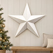Extra large white metal star on a cream panelled hallway wall