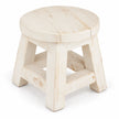 White rustic wooden mini stool with a round top, splayed legs and lower crossbars, shown alone against white.