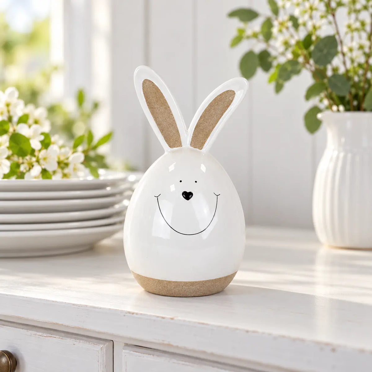 White ceramic rabbit beside stacked white plates on a kitchen dresser.