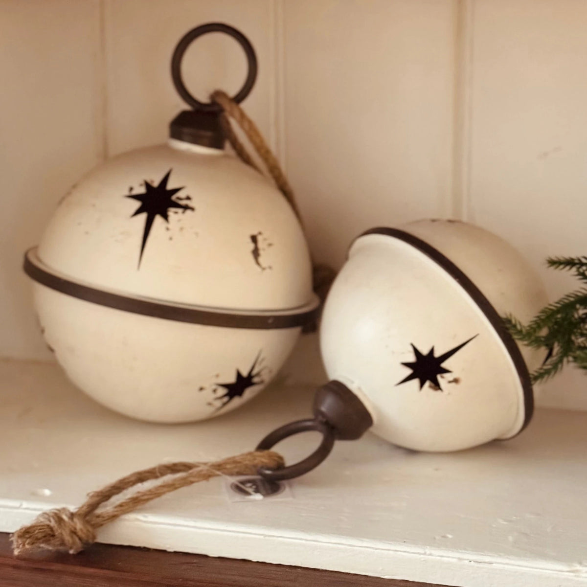 White Round Hanging Metal Bells, two white metal bells on a light shelf