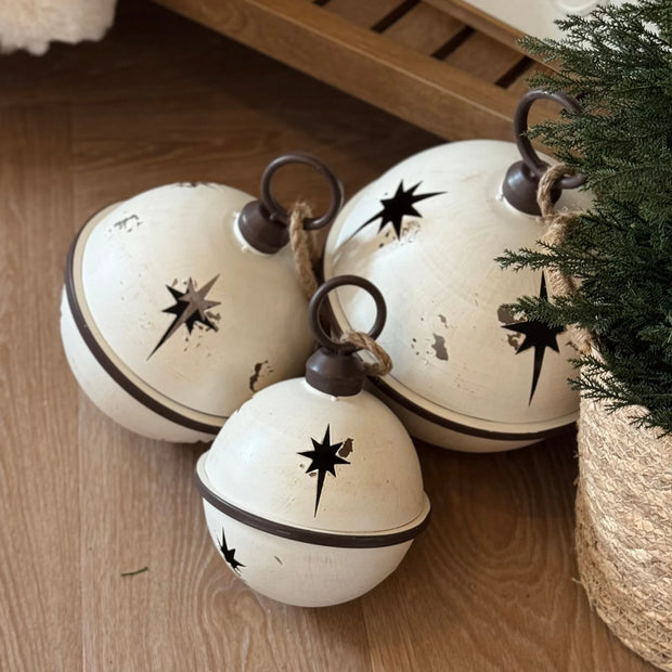 White Round Hanging Metal Bells, white metal bells grouped on a wooden shelf beside greenery