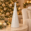 large white scalloped glazed ceramic Christmas tree in a festive Christmas setting with sparkling warm fairy lights