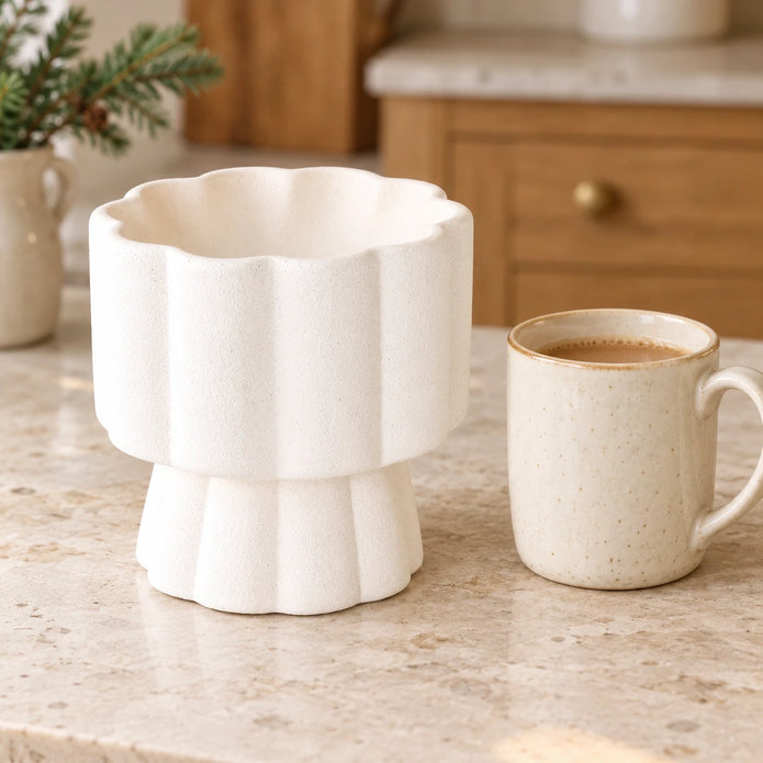 White scalloped pedestal wax melt and oil burner by Something Different Wholesale beside a kitchen scale