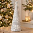 large white star glazed ceramic Christmas tree in a festive setting with warm sparkling Christmas lights