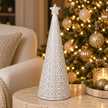 large white star glazed ceramic Christmas tree in a festive setting with warm sparkling Christmas lights