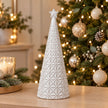 medium white star glazed ceramic Christmas tree in a festive setting with warm sparkling Christmas lights