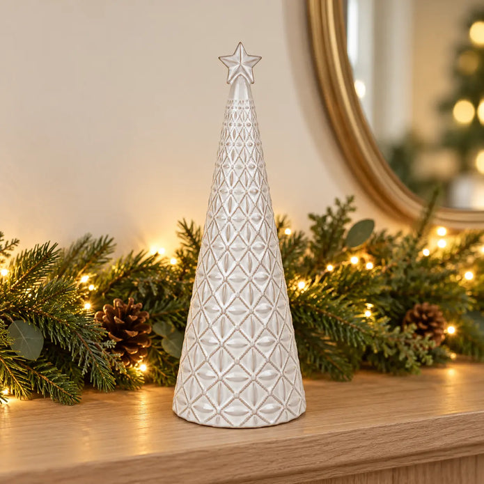 medium white star glazed ceramic Christmas tree in a festive setting with warm sparkling Christmas lights