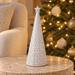 medium white star glazed ceramic Christmas tree in a festive setting with warm sparkling Christmas lights