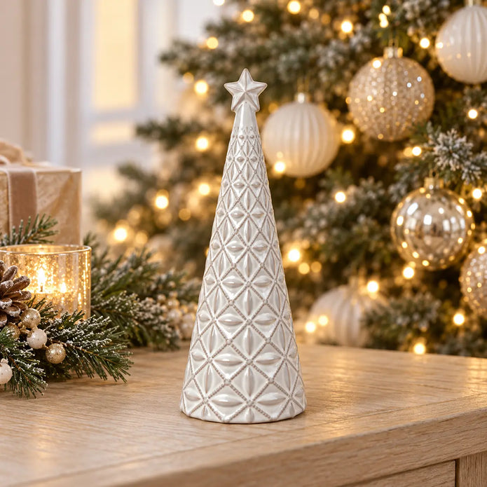 small white star glazed ceramic Christmas tree in a festive setting with warm sparkling Christmas lights