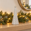small white star glazed ceramic Christmas tree in a festive setting with warm sparkling Christmas lights