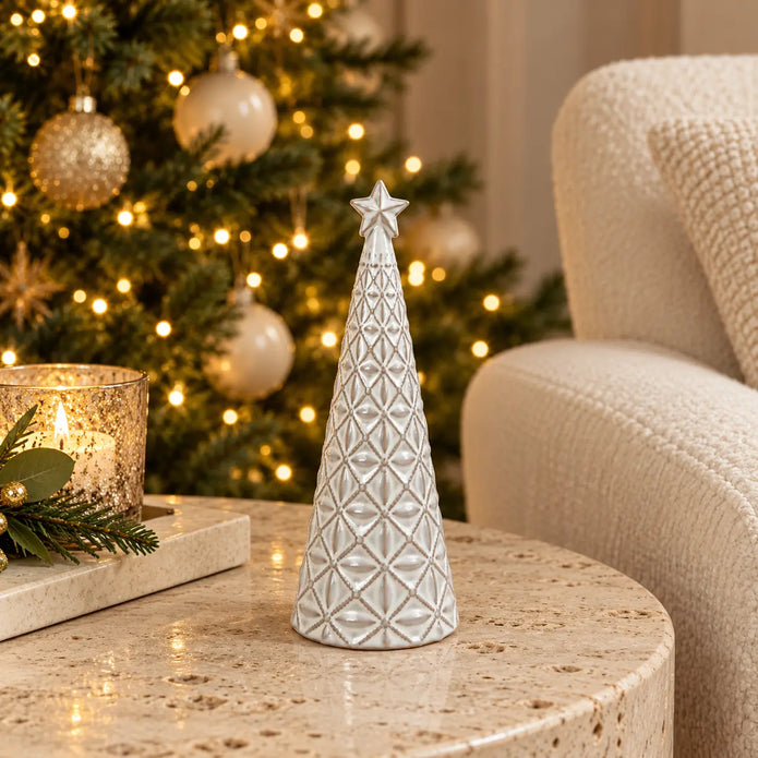 small white star glazed ceramic Christmas tree in a festive setting with warm sparkling Christmas lights