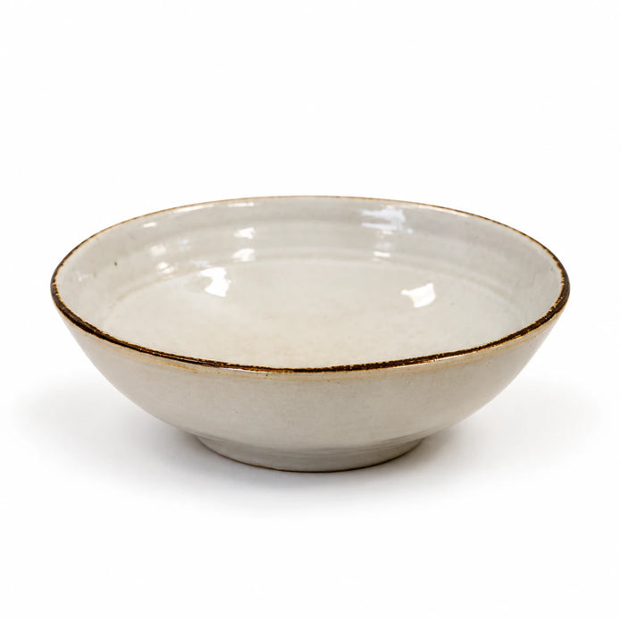 Empty white stoneware cereal bowl with brown rim on a white background