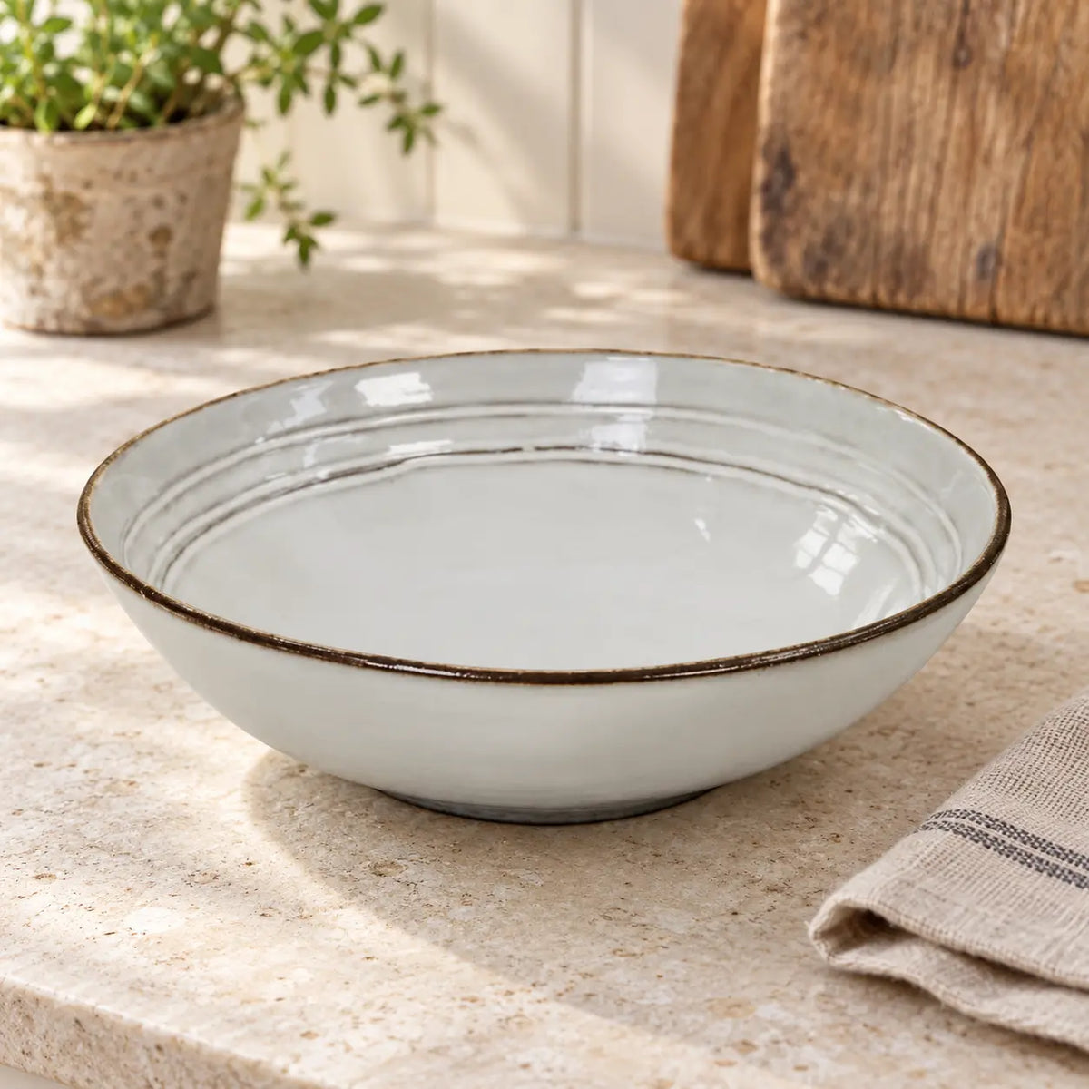 Empty white stoneware pasta bowl showing its ridged interior on a light kitchen counter