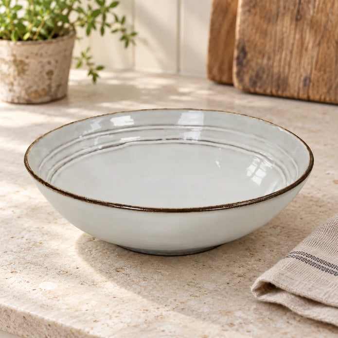 Empty white stoneware pasta bowl showing its ridged interior on a light kitchen counter