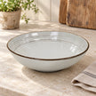 Empty white stoneware pasta bowl showing its ridged interior on a light kitchen counter