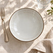 Overhead view of white stoneware pasta bowl on an ivory linen table setting