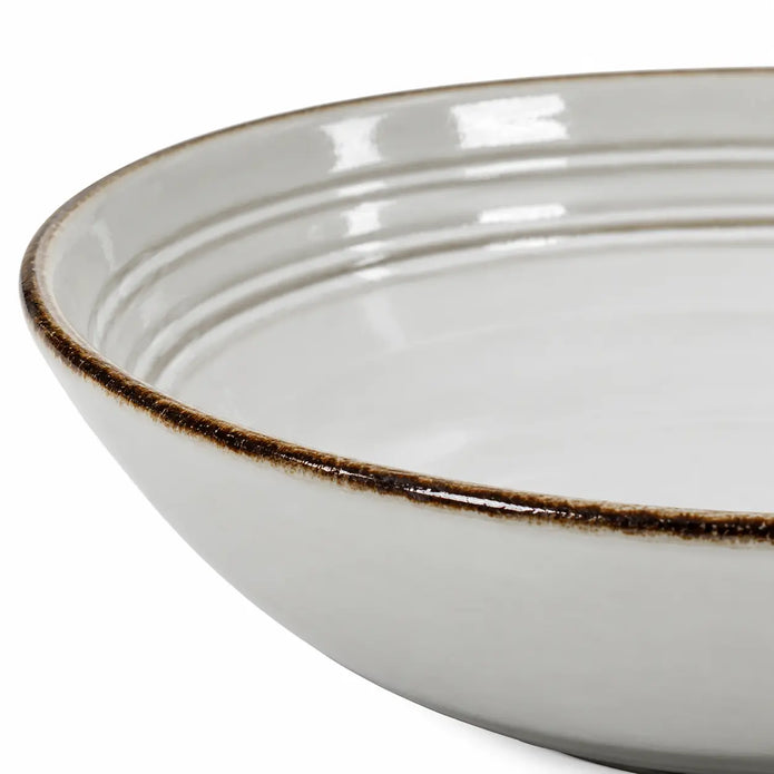 Close-up of the dark rim, white glaze and inner ridges of the stoneware pasta bowl