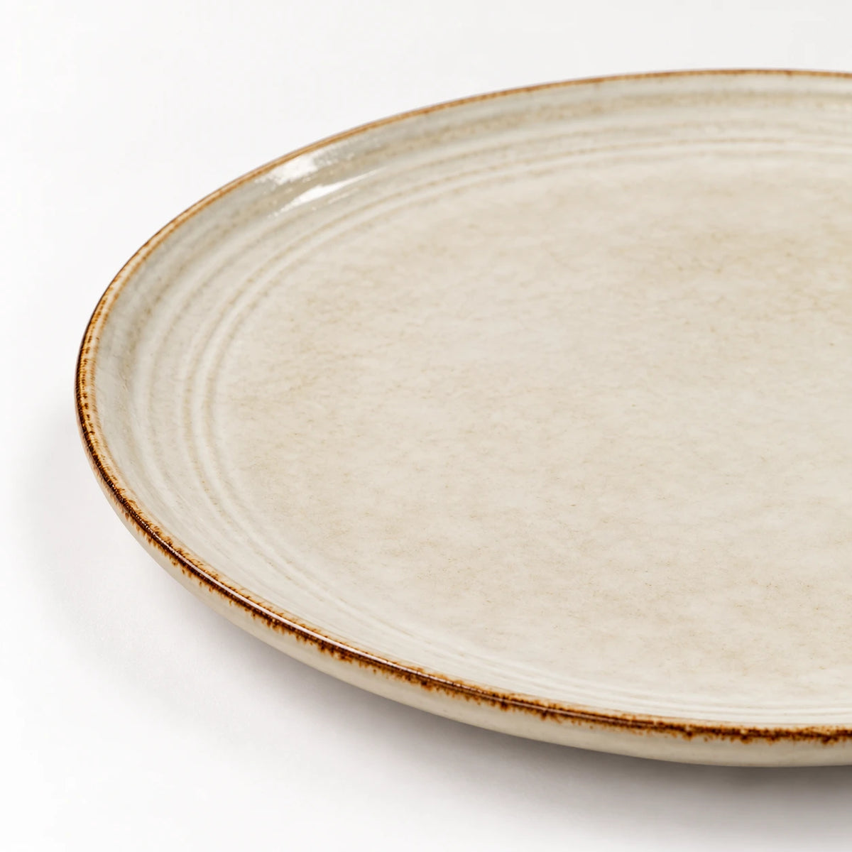Close-up of the brown rim and concentric glazed rings on the white stoneware side plate