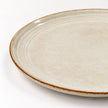 Close-up of the brown rim and concentric glazed rings on the white stoneware side plate