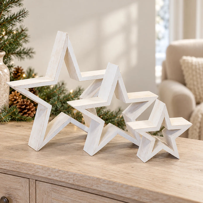 Set of three white wooden stars styled on an oak console with Christmas greenery
