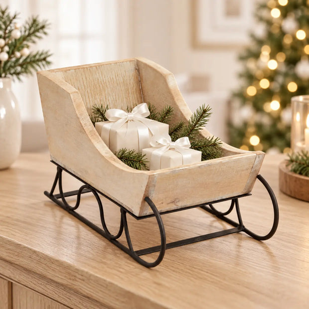 Whitewashed wooden Christmas sleigh from Hill Interiors' Wash Collection, decorated with festive holiday accents.