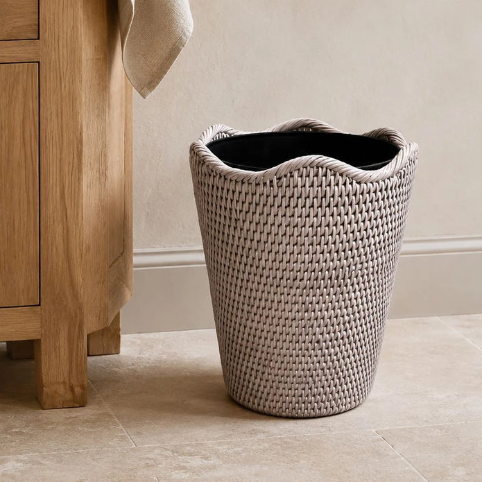Wickham Rattan Round Lined Waste Paper Bin, pale woven waste bin with dark lining beside a wooden cabinet