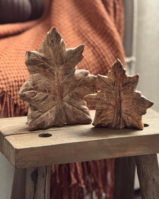 Wooden leaf sculptures on a wooden surface with a blurred background