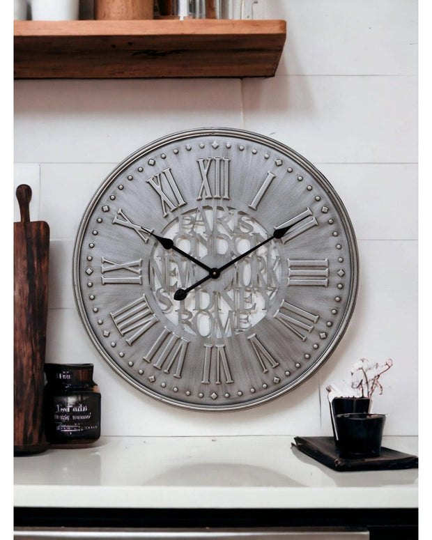 Grey metal wall clock by Widdop & Co with black hands and minimalist design, hanging on a white wall.