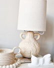 Small cream ceramic table lamp with a ceramic handle and linen shade, perfect for cozy lighting in living spaces.