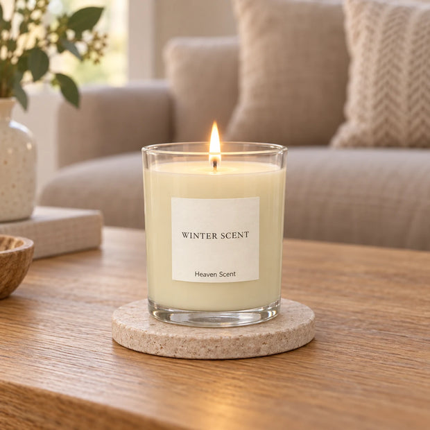 Heaven Scent Winter Scent Medium Candle, lit in clear glass on a stone coaster in a living room