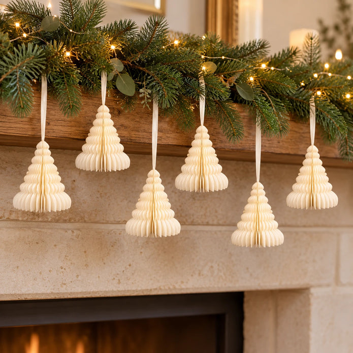 Six ivory paper Christmas trees suspended beneath a festive mantel garland.